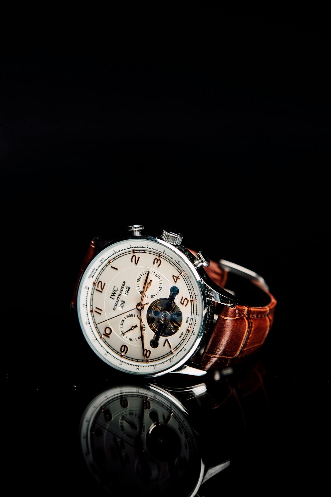 Close-up of a mechanical watch with a cream dial and brown leather strap